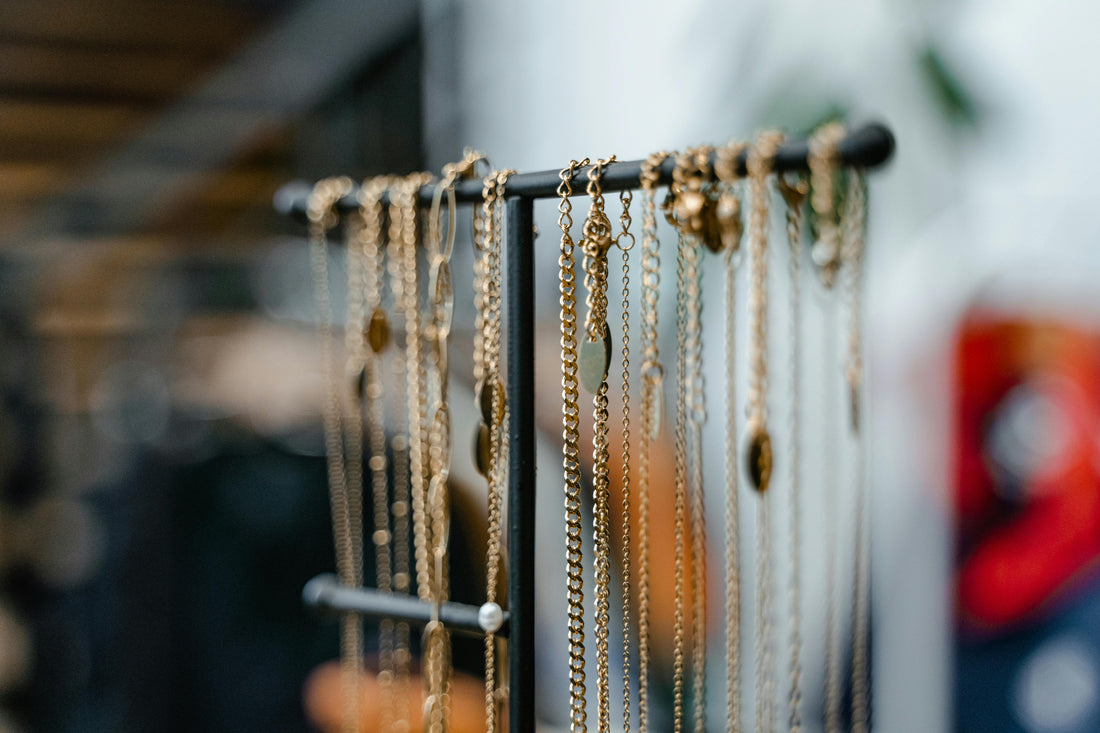 Bijoux couleur or suspendus sur une barre de présentation avec fond flou